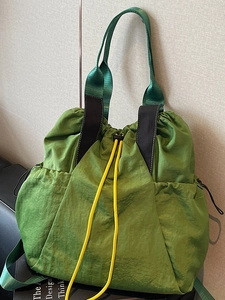 Grass green nylon drawstring tote bag with woven handles and yellow cords
