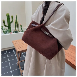 Detailed close-up of dark brown suede tote bag with metallic buckle and shoulder straps