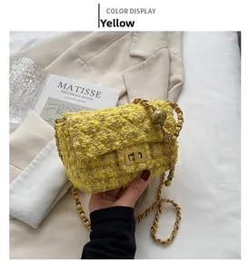 Detail of yellow tweed crossbody bag with gold metal lock and chain strap