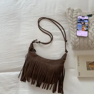 Close-up of a brown suede tassel shoulder bag with retro half-moon design and long fringe
