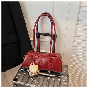 Close-up of red patent leather Boston bag with metal logo and cute plush bear charm detail
