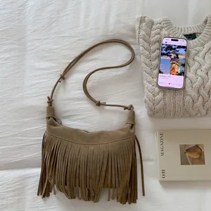 Detail view of brown suede crescent bag with long fringe on a white textured background