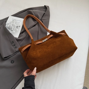 Close-up of brown suede bucket bag with leather handles and metallic buckle on a suit jacket