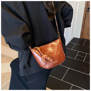 Detail of brown half-moon crossbody bag with glossy oil-wax texture and chain strap