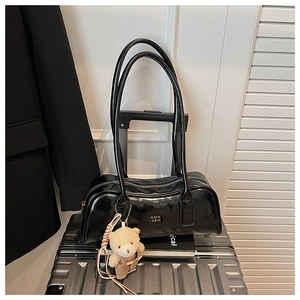 Detail of glossy black Boston bag featuring COIH 2DN logo and cute plush bear charm