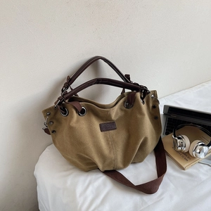Detail of khaki canvas tote bag with brown leather handles and casual laptop setting