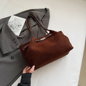 Detail of dark brown matte tote bag with metal buckle on a grey suit background