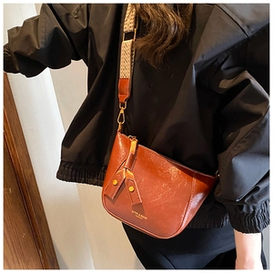 Close-up of vintage brown crossbody bag with wide geometric pattern jacquard shoulder strap