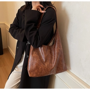 Detailed side view of a large vintage brown tote bag worn over the shoulder for daily commute