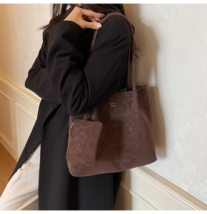 Detail of dark brown tote bag set with textured faux leather and gold logo for work