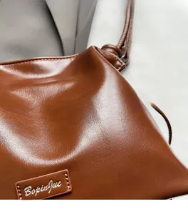 Detailed macro view of the brown leather texture and logo plaque on the bucket bag
