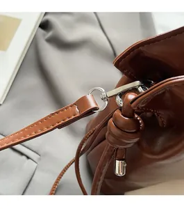 Detail of dark brown leather bucket bag with silver hardware and unique side knot accents