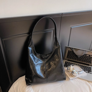 Detail shot of the black leather tote bag with pleated texture used in an office setting