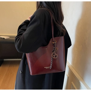 Detail of dark red leather tote bag with unique pretzel charm and gold lettering