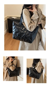 Detail of glossy black quilted puffer tote bag with wide nylon straps and spacious design
