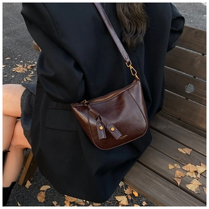 Dark brown faux oil wax leather crescent bag with wide strap and tassel details