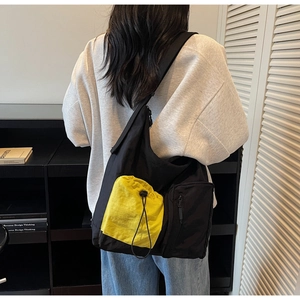 Detail of crossbody messenger bag with high-capacity black nylon and yellow drawstring pocket