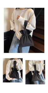 Detail van de zwarte emmer-tas met trekkoord, van duurzaam nylon en geplooide sluitingsdetails