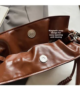 Detailed close-up of the silver magnetic buckle closure on a brown leather bucket bag