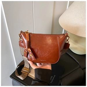 Detail of caramel brown PU leather crossbody bag with wide woven jacquard strap