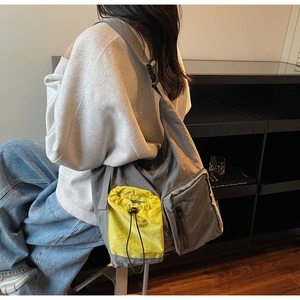 Detail of grey crossbody messenger bag with yellow drawstring pocket and layered structure