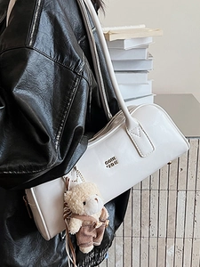 White minimalist Boston handbag with gold logo and plush bear charm for autumn 2025 style