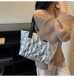 Silver quilted tote bag detail showing metallic texture and black fabric handles