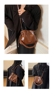 Detail of dark brown leather bucket bag with braided handle and drawstring closure