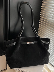 Minimalist black frosted bucket bag with leather strap and silver buckle on white book