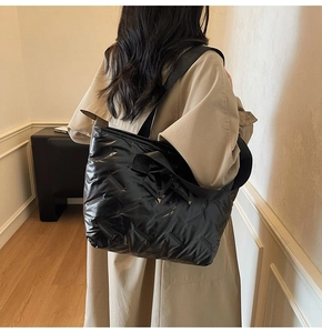 Close-up of black quilted shoulder bag featuring glossy waterproof nylon and geometric texture