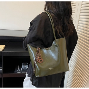 Close-up of olive green leather tote bag with vintage charm and retro side pendant
