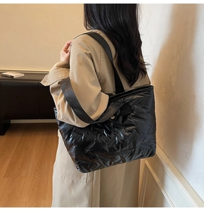 Close-up of black quilted puffer tote bag on shoulder with sleek nylon finish