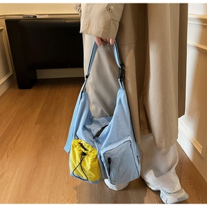 Detail view of a light blue nylon crossbody bag featuring a bright yellow drawstring pocket