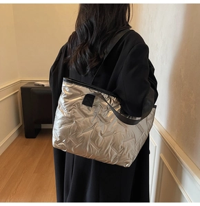 Silver quilted tote bag shown on model, highlighting large capacity and metallic texture