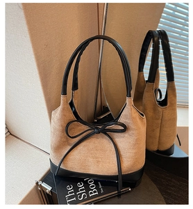 Détail du cabas en daim kaki et cuir noir avec nœud minimaliste et finitions soignées