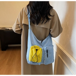 Detail view of a large capacity light blue nylon crossbody bag with yellow drawstring pocket