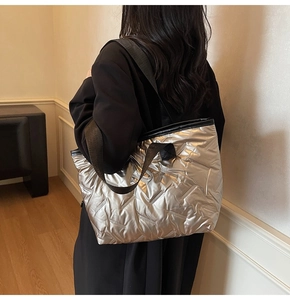 Detailed view of silver quilted tote bag with metallic texture and black shoulder strap