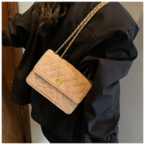 Detail of light beige quilted crossbody bag with golden chain and metallic turn-lock