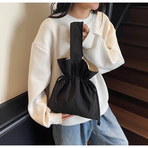 Detailopname van zwarte bucket bag met trekkoord en geplooide nylon stof en riem
