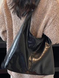 Classic black glossy hobo bag with large capacity shown on model as an underarm tote