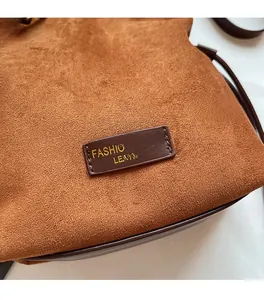 Détail du sac à bandoulière en daim marron avec texture douce et chaîne dorée