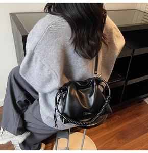 Detailed close-up of a black leather bucket bag with a unique spiral handle and drawstring
