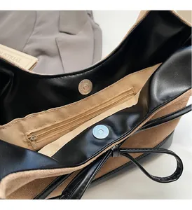 Détail du grand sac cabas montrant le cuir noir, le daim marron et les fermoirs magnétiques
