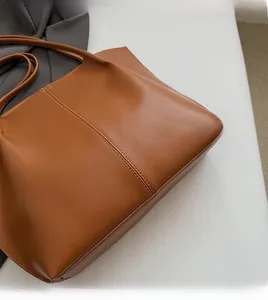 Close-up of brown leather tote bag with vertical stitching and smooth leather texture