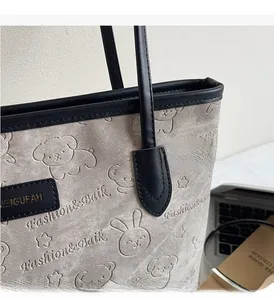 Close-up of embossed cartoon bear patterns and leather piping on the grey tote bag