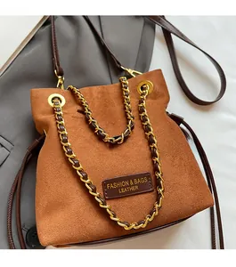 Détails de ce sac seau en daim marron avec chaîne dorée et étiquette en cuir