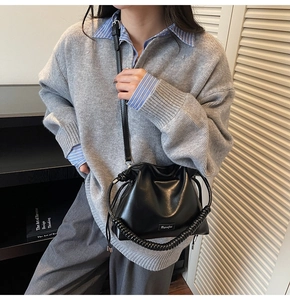 Detailed view of black pleated crossbody bucket bag with glossy finish and spiral handle