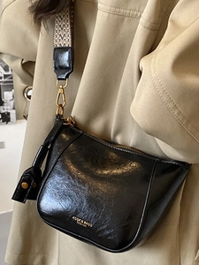 Minimalist black crossbody bag with wide jacquard strap and golden metal buckle details