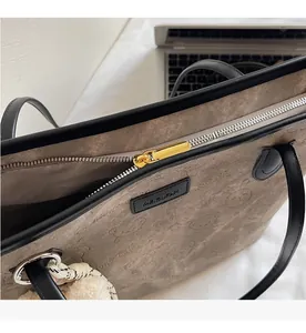Close-up of smooth gold zipper and bear embossed canvas texture on brown tote bag