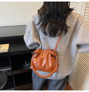 Detail of caramel brown bucket bag with pleated design and spiral top handle